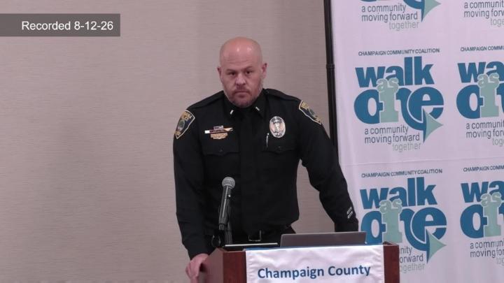 Police Representative speaking at podium in front of Walk as One banner.